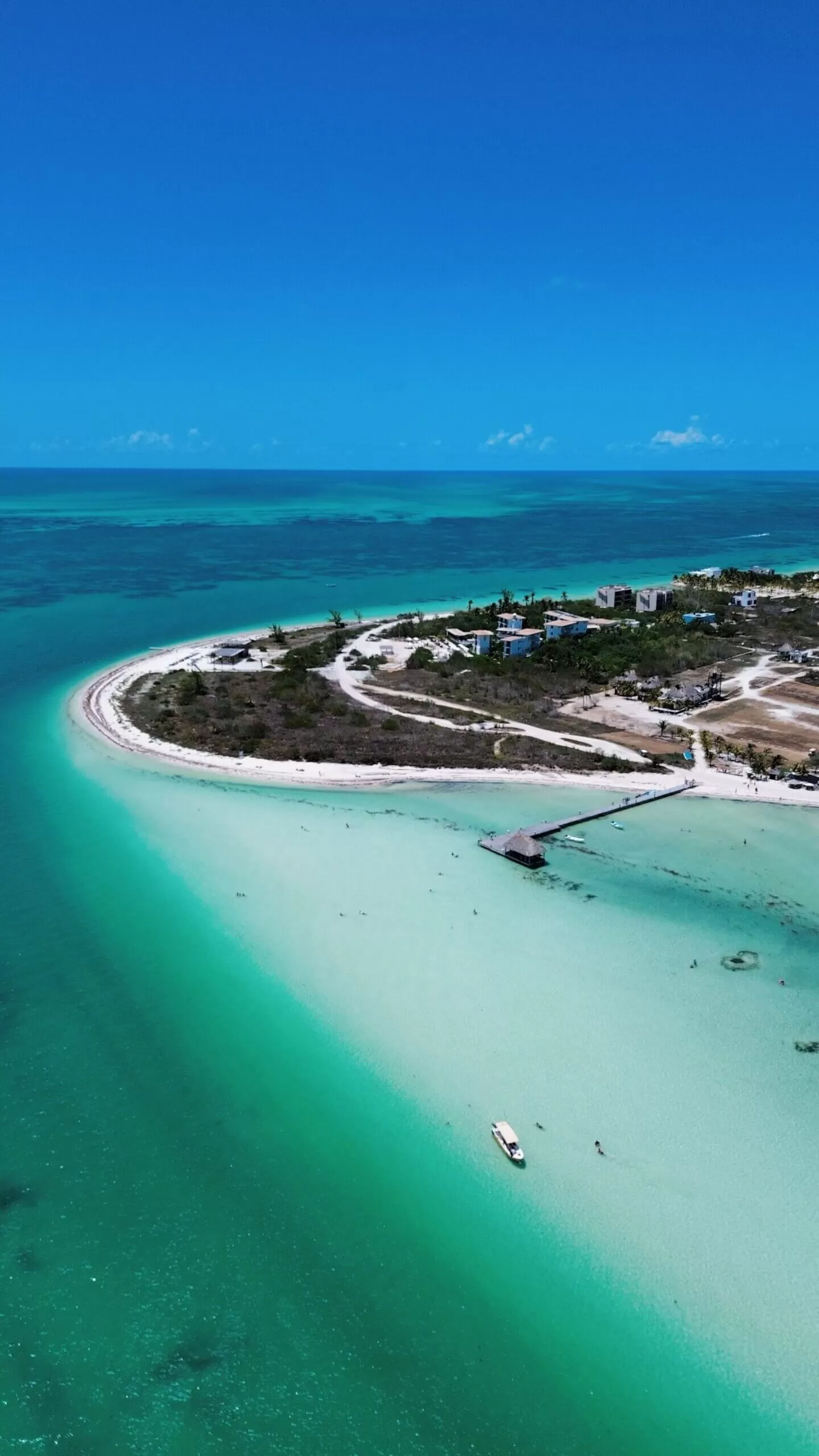foto de punta cocos tomada con el drone. se ve la playa, el mar y algunos muelles. el agua es verde, celeste y azul