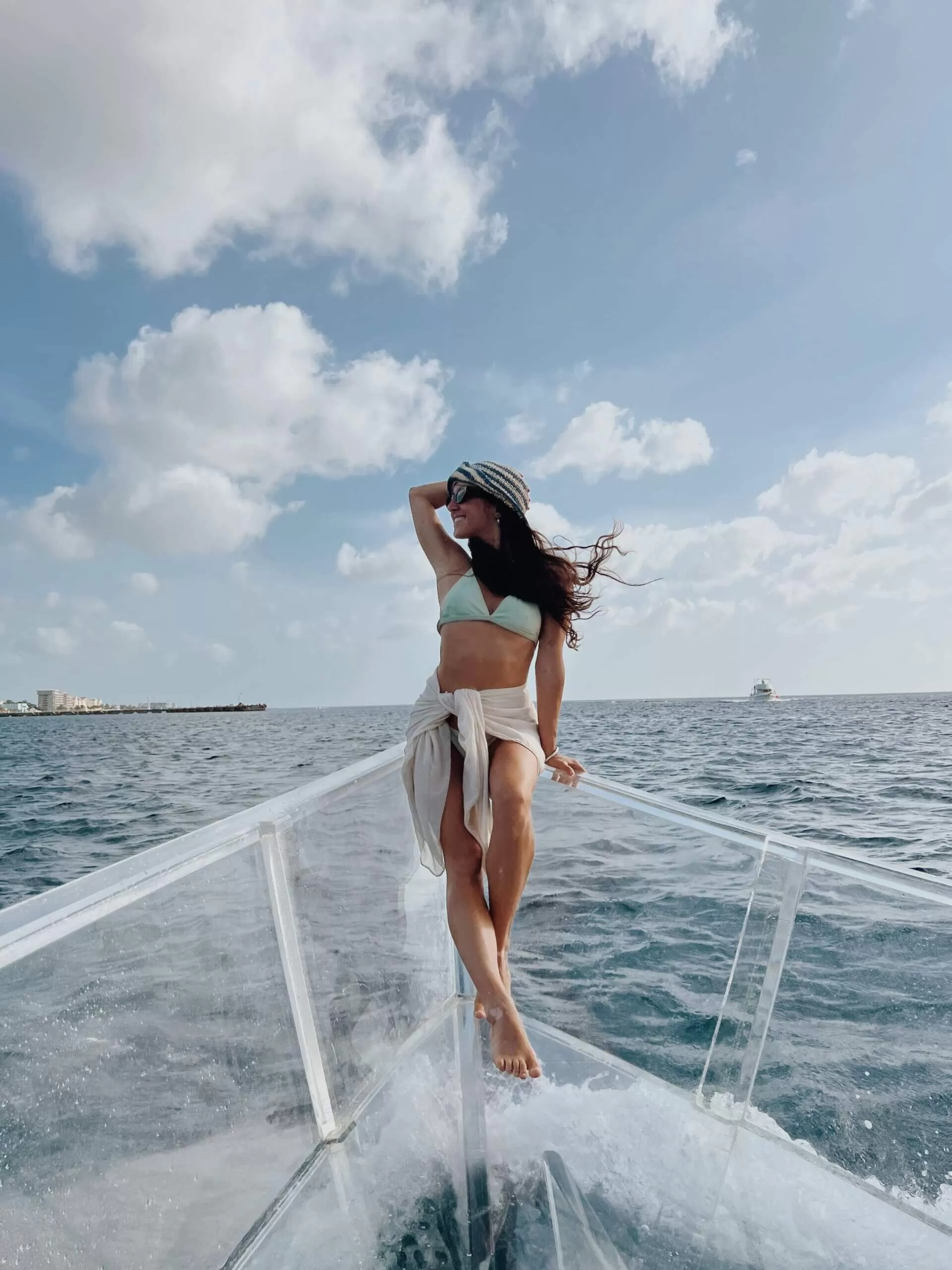 estoy yo (juli) sentada en la punta de un bote transparente. de fondo el mar