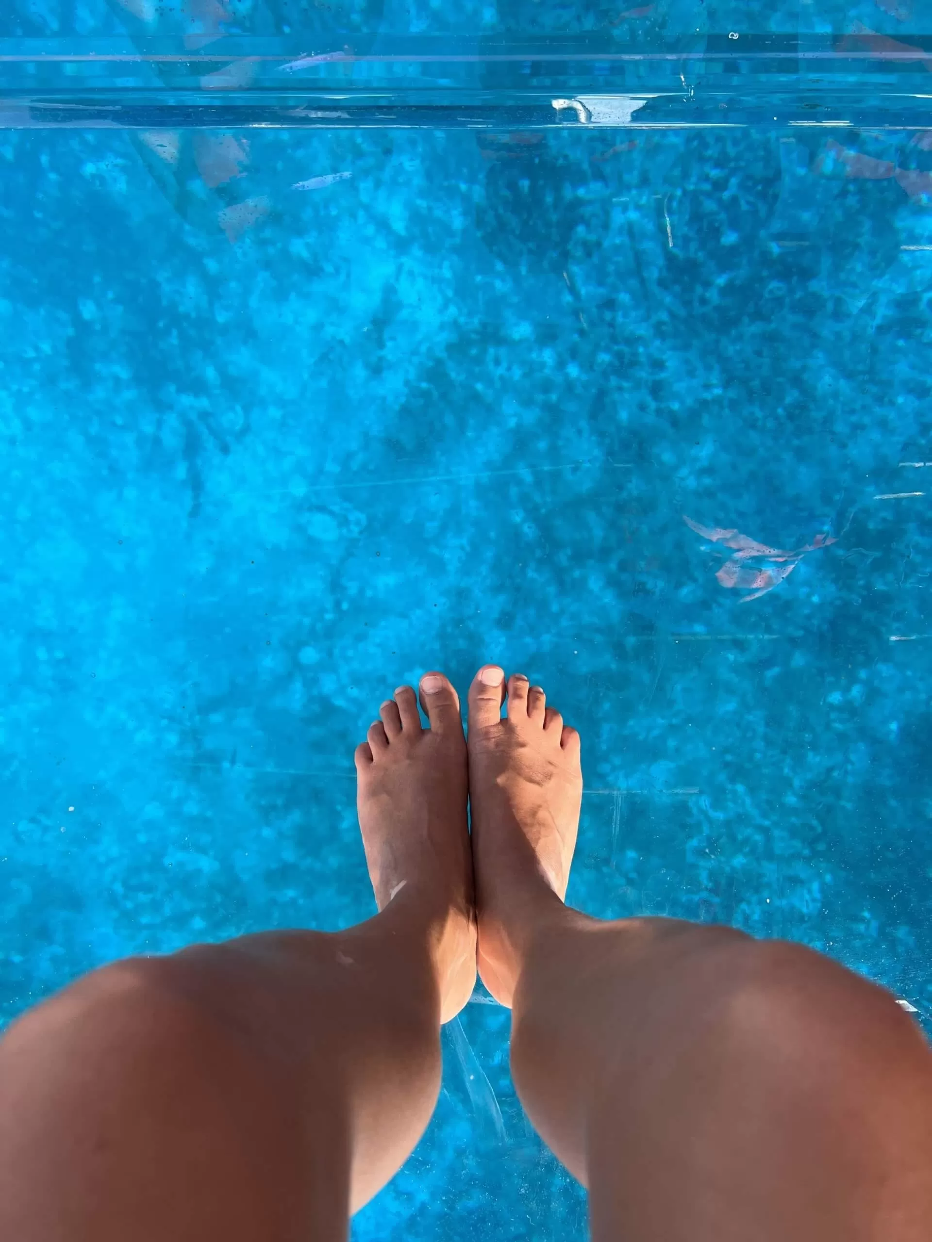 foto tomada a mis pies sobre el piso de una lancha transparente. abajo se ve el mar