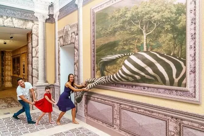 foto del museo de las maravillas 3 d en playa del carmen. se ve una familia agarrando la pata de una zebra (animal) que aparenta salir de un cuadro