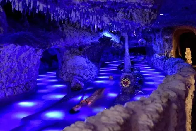 parque xplor en playa del carmen. se ve una familia nadando en rios subterraneos en una especie de caverna con estalactitas