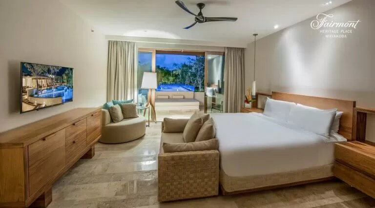 foto de la habitacion del Fairmont Heritage Playa del Carmen. se ve una cama amplia . un gran ventanal que da a la pileta