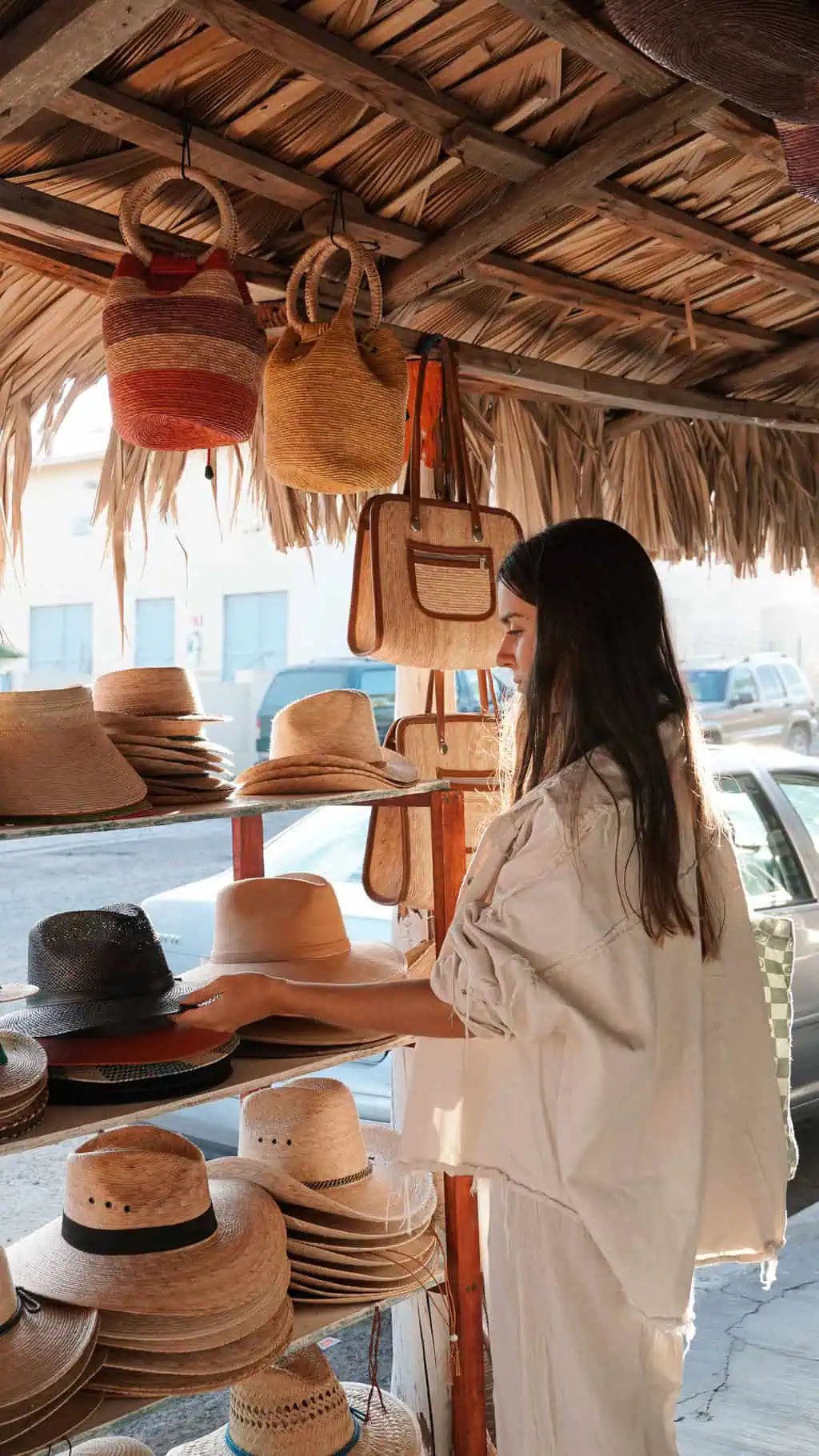 pau viendo sombreros de uno de los puestos de artesanias en todos santos