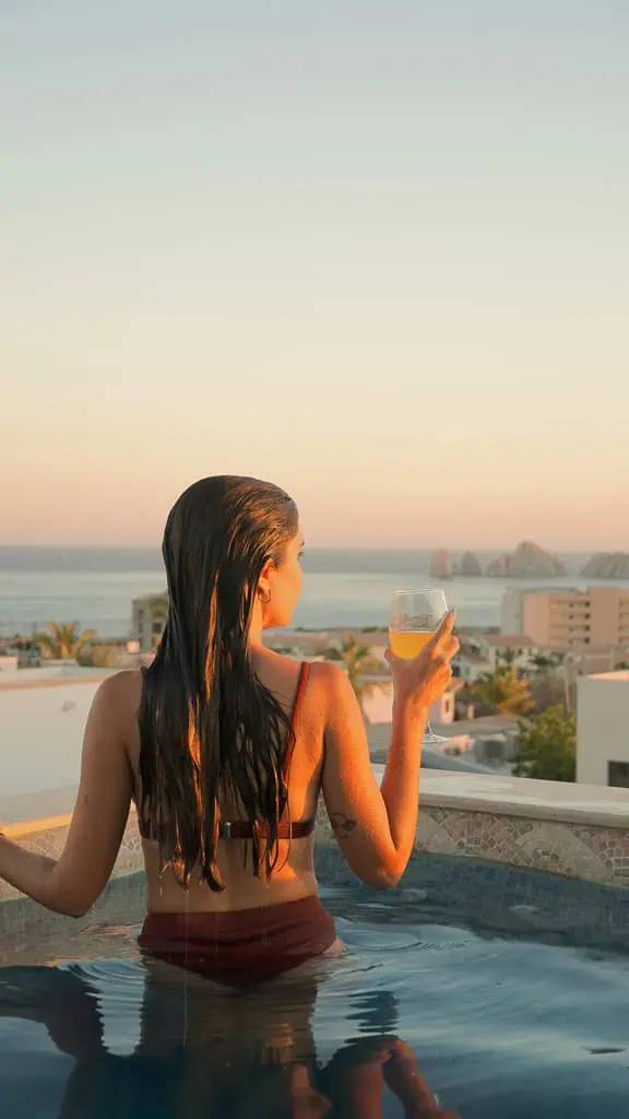 pau tomando un trago en una pileta en una terraza en un aribnb que nos alojamos con vista al mar y a los cabos de san lucas