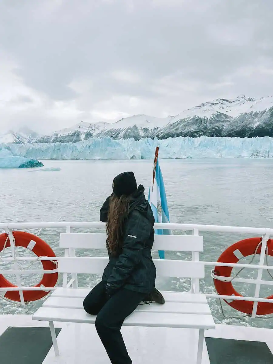 pau sentada en un barco mirando al glaciar en el medio de la navegacion