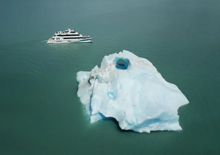 Foto aérea del crucero gourmet en el medio del lago con un iceberg al costado