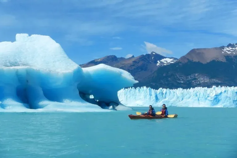 gente andando en un kayak en el medio del lago y de fondo el glaciar perito moreno