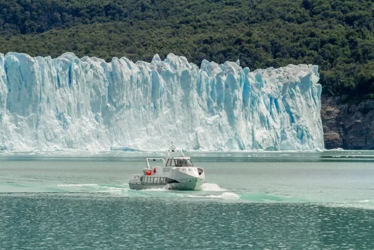 lancha en el medio del lago y de fondo el glaciar perito moreno