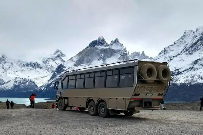 un gran colectivo 4 x4 y de fondo montañas nevadas de las torres del paine